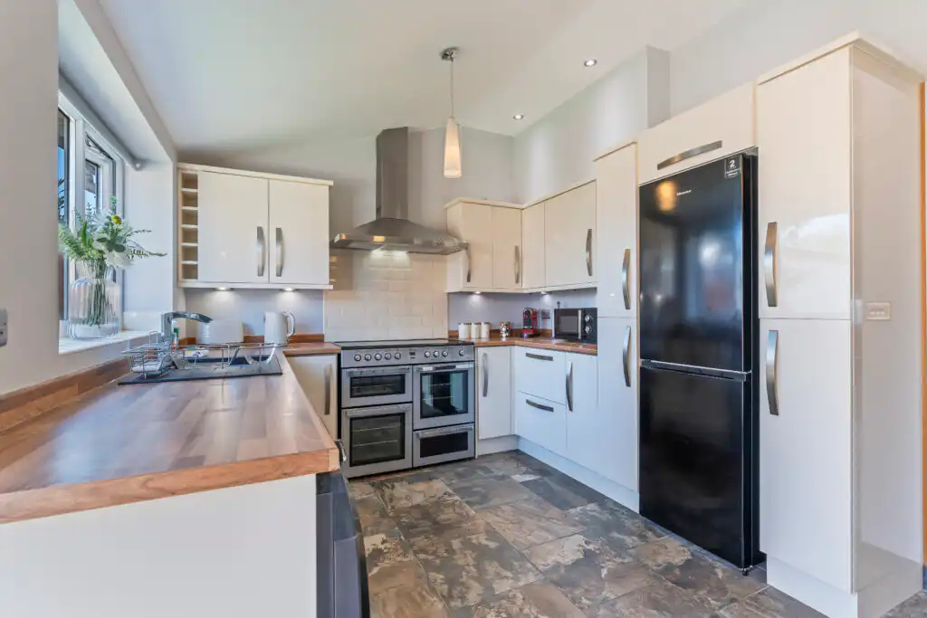 Modern white kitchen with wooden countertops and black refrigerator