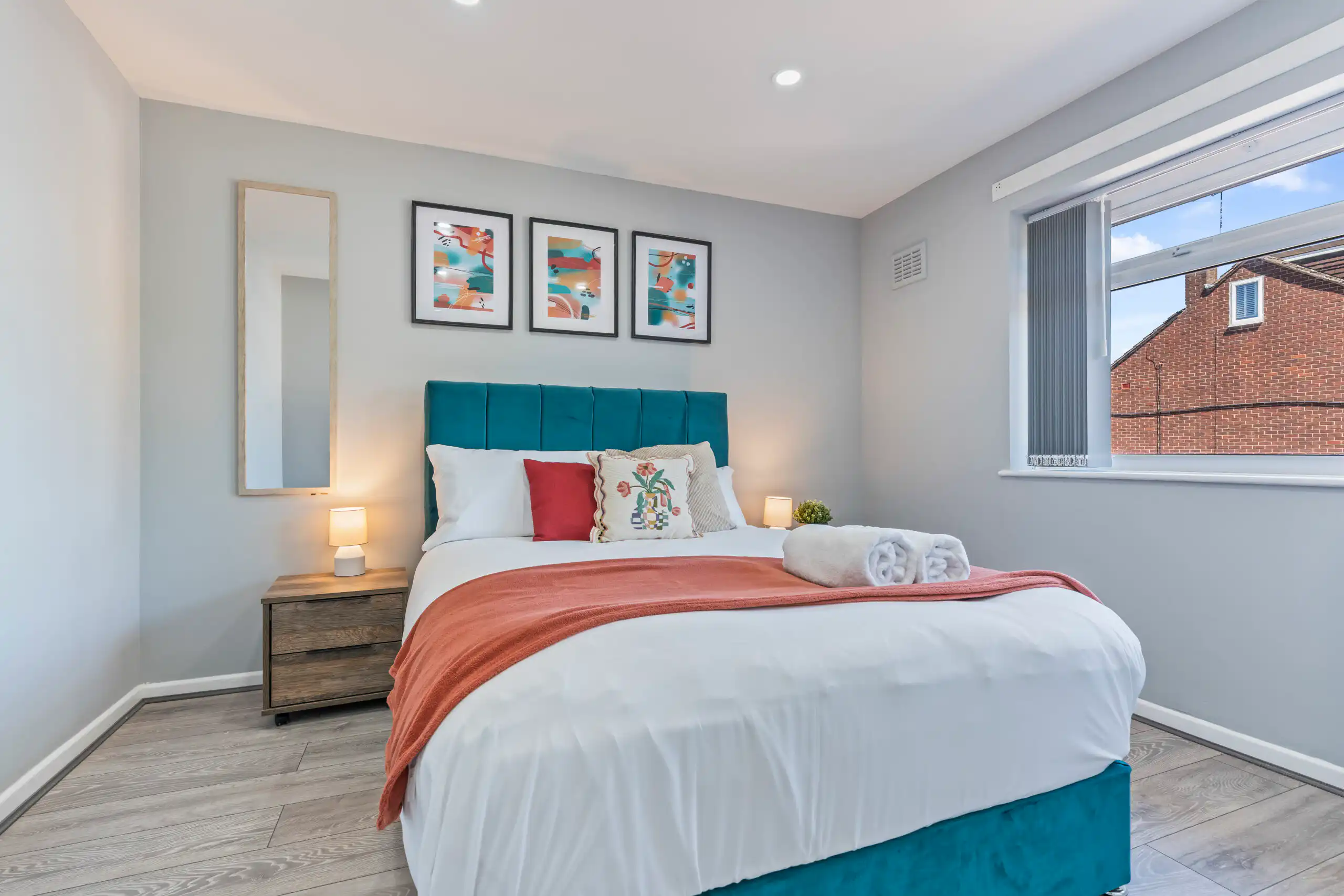 Modern bedroom with teal bed and coral throw