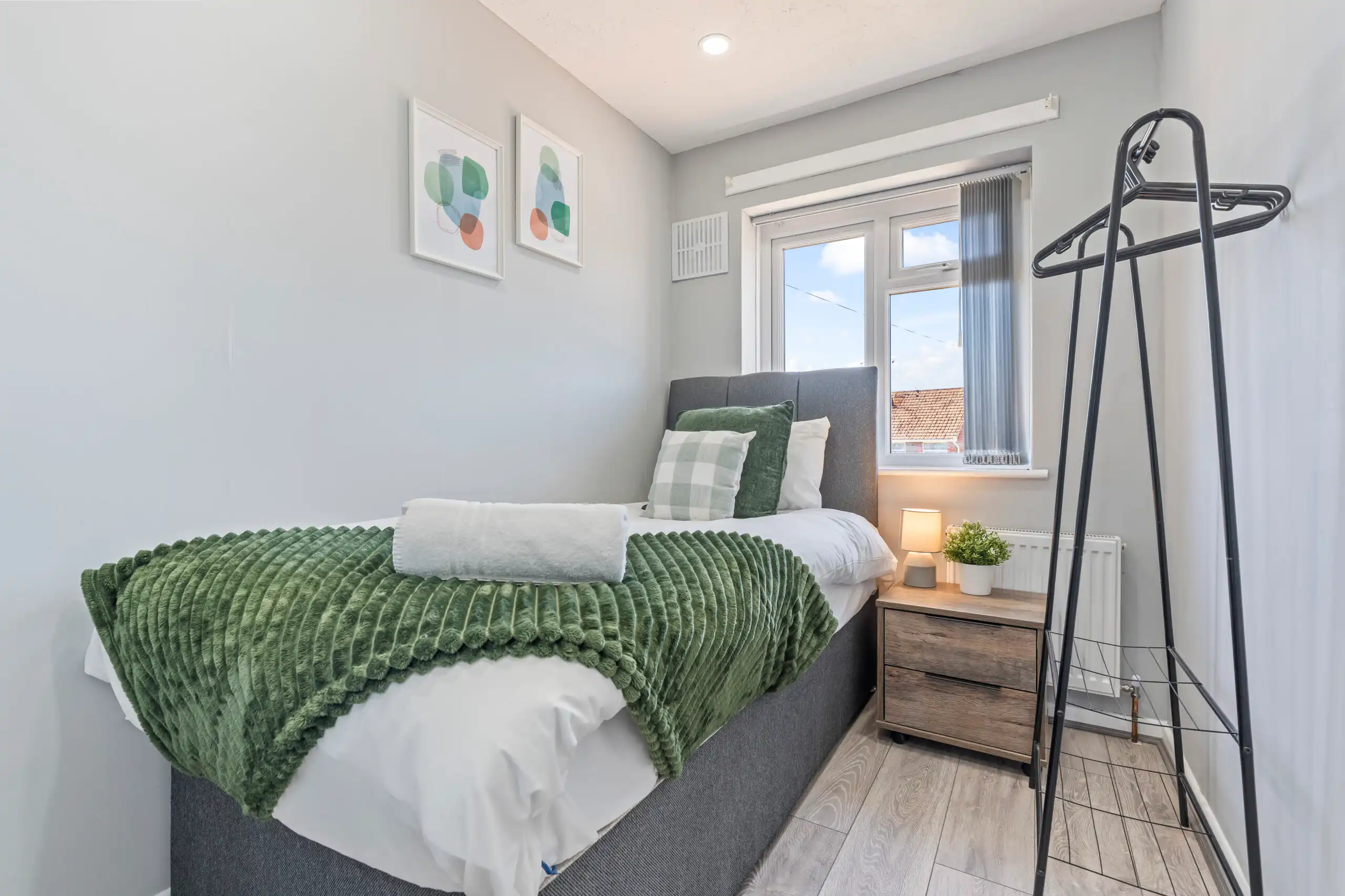 Modern small bedroom with green throw and window