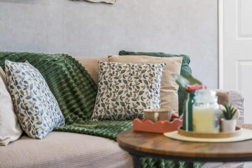 Cozy sofa with green throw and patterned pillows