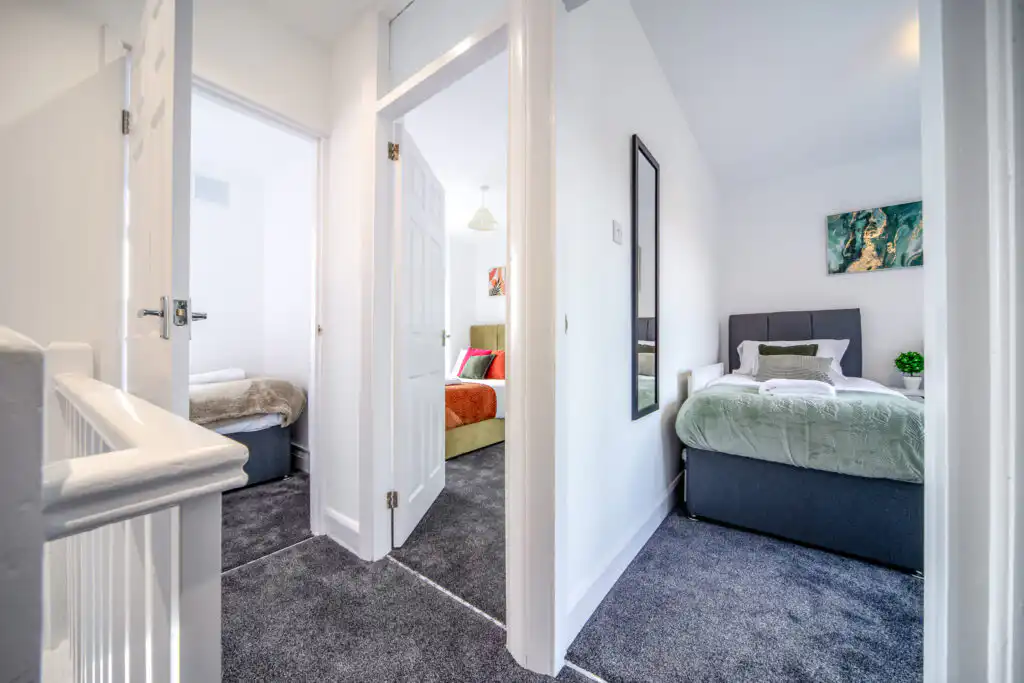 Hallway view of two modern bedrooms with gray carpet