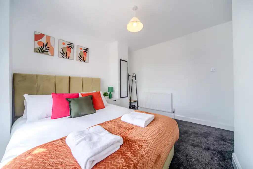 Modern bedroom with orange throw and colorful pillows