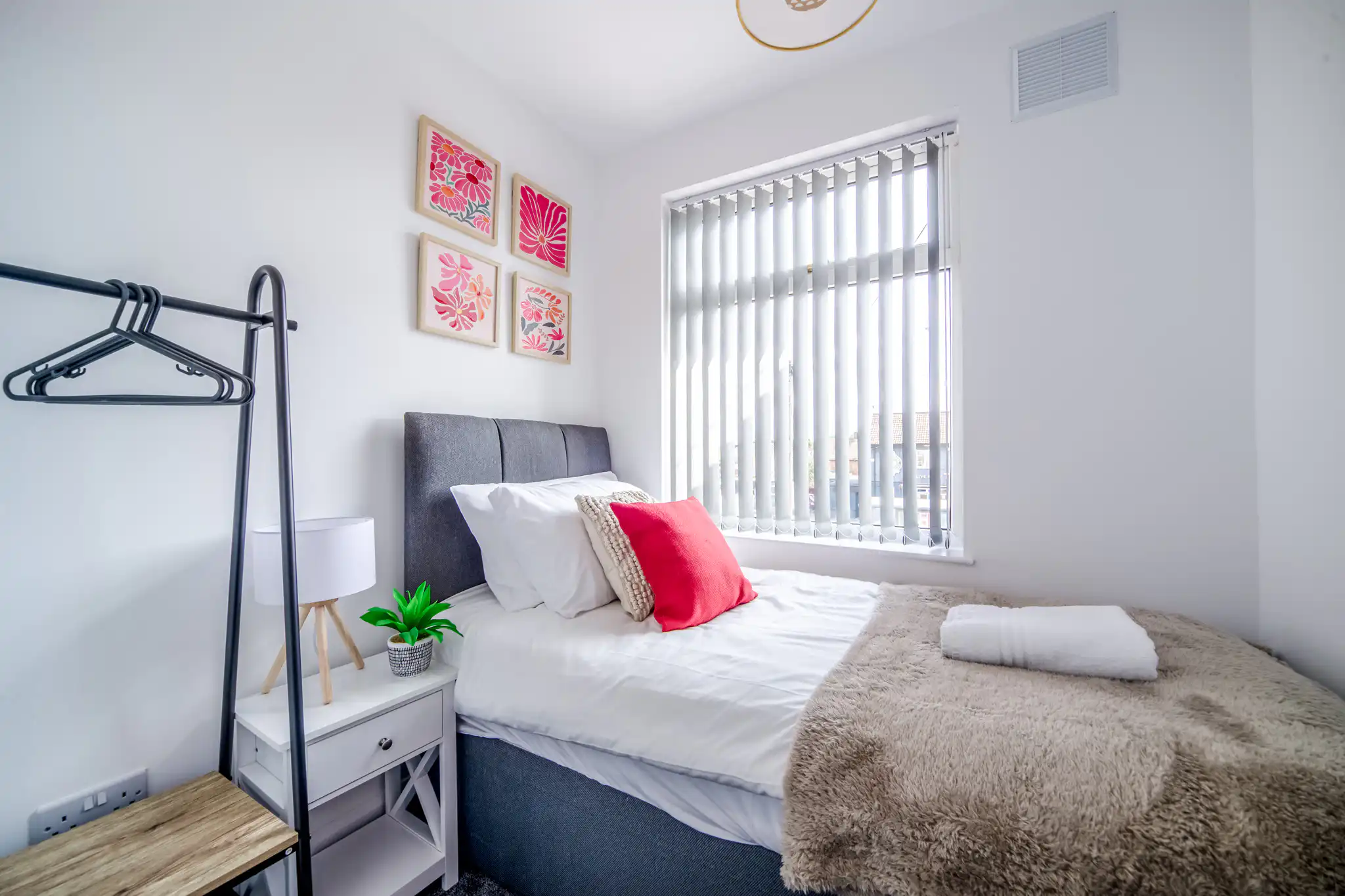 Bright minimalist bedroom with single bed and pink accents