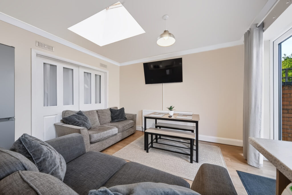 Bright living room with gray sofas, skylight, and wall TV