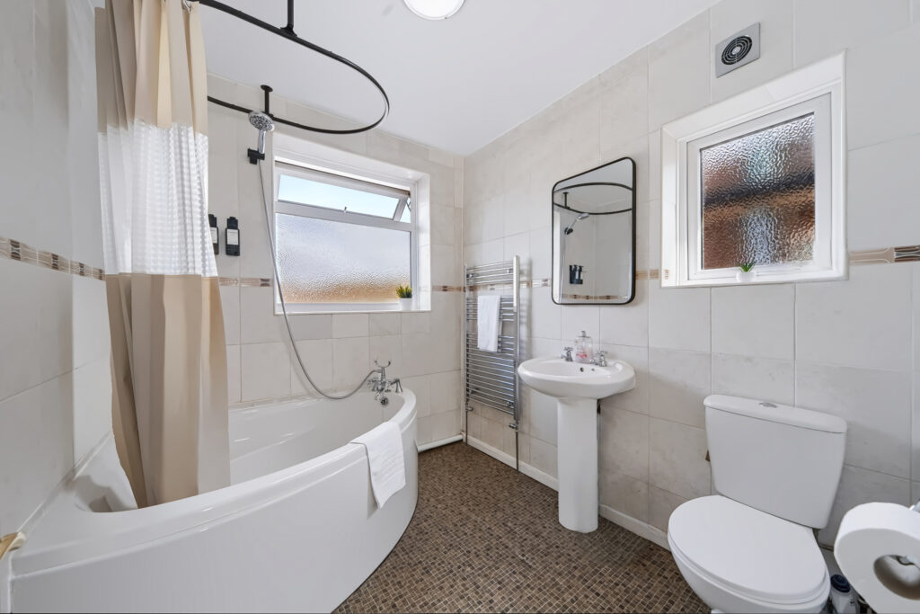 Bright tiled bathroom with bathtub, shower, sink, and toilet
