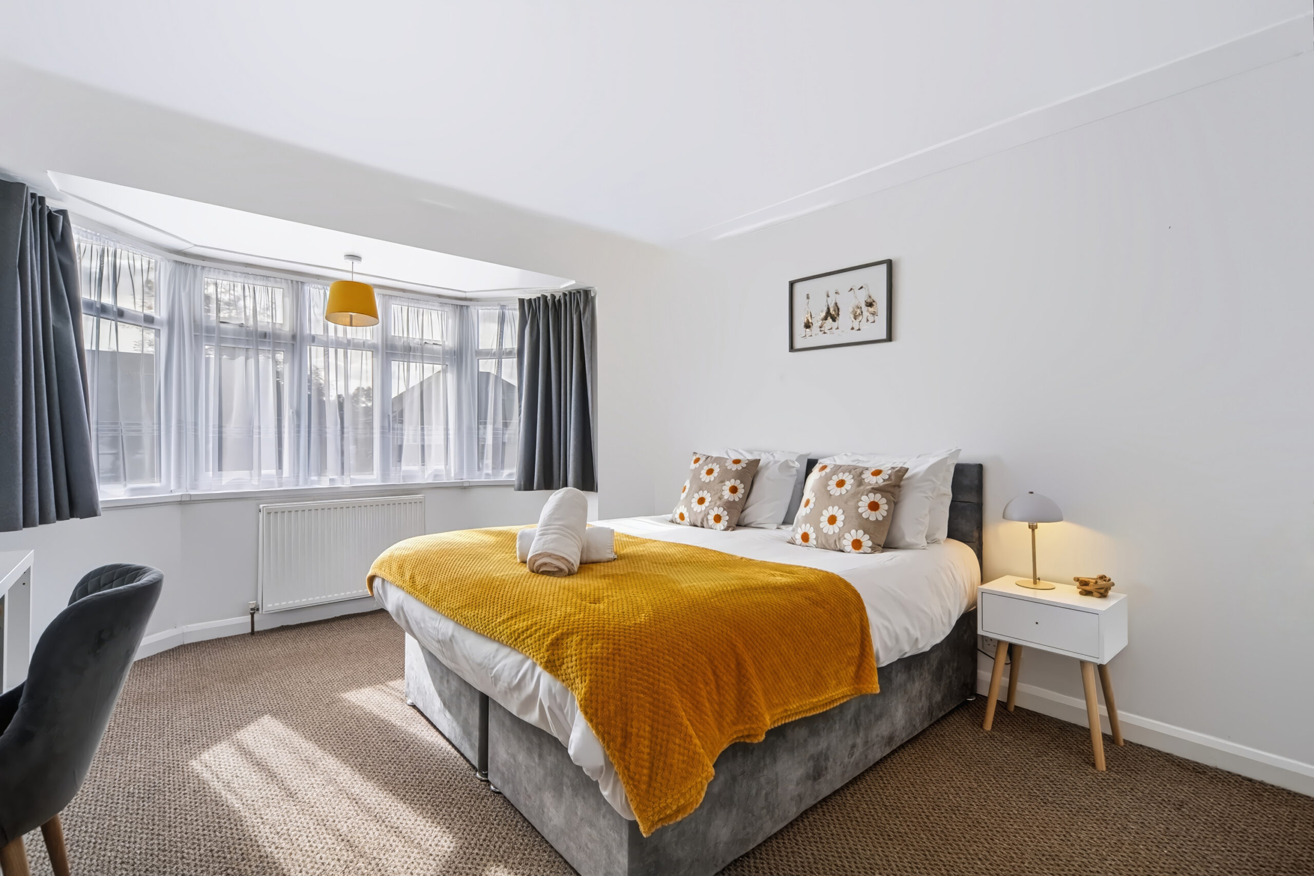 Sunlit bedroom with mustard throw and gray curtains