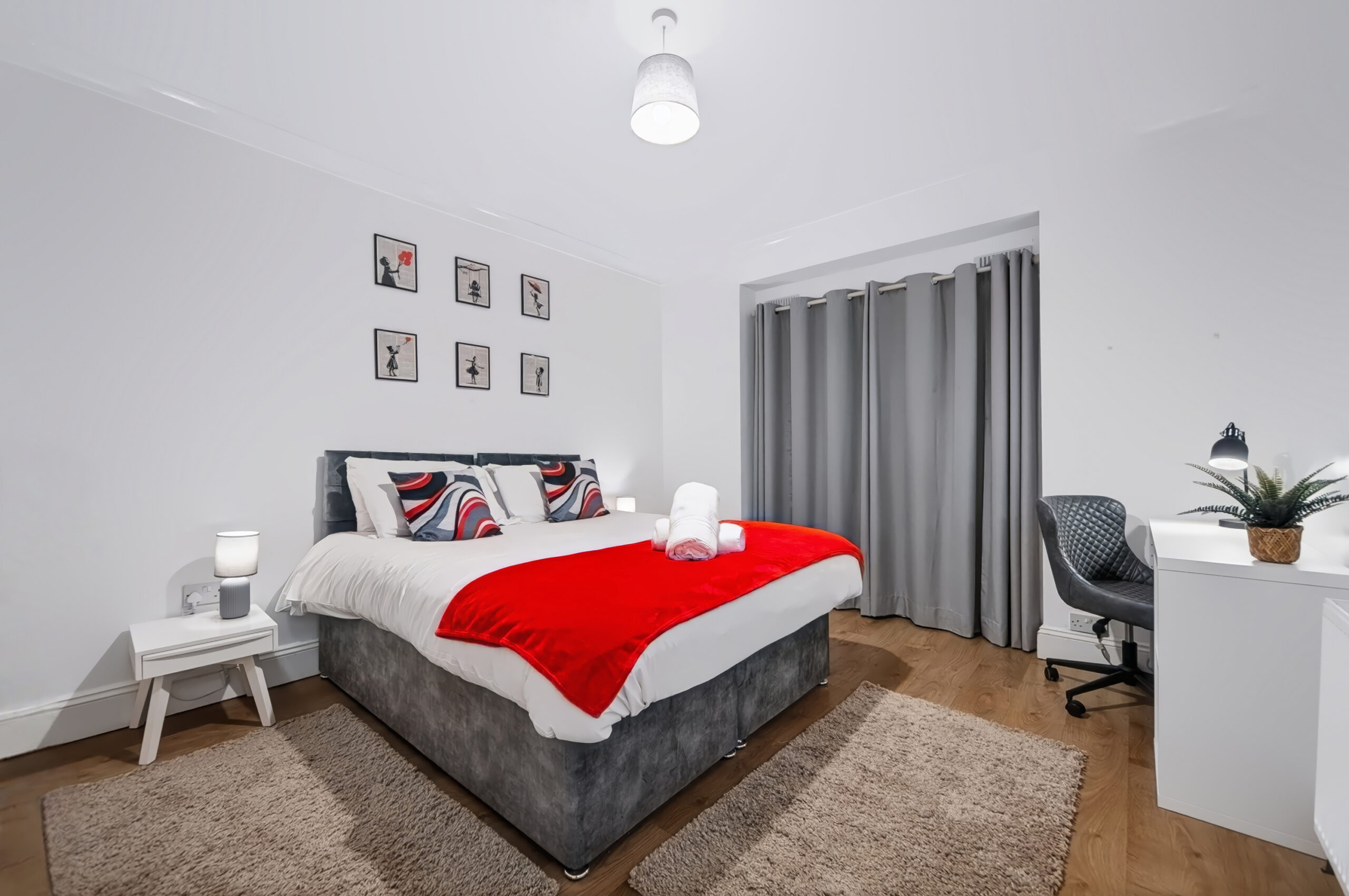 Modern bedroom with red throw, desk, and gray curtains