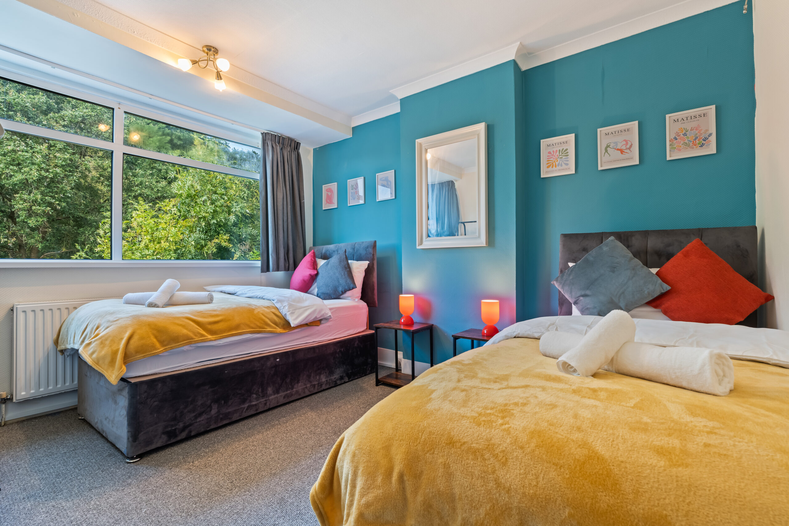 Colorful twin bedroom with teal walls and mustard blankets